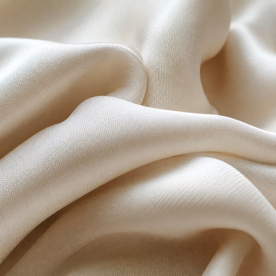 Macro photograph of ivory silk crepe in soft folds.